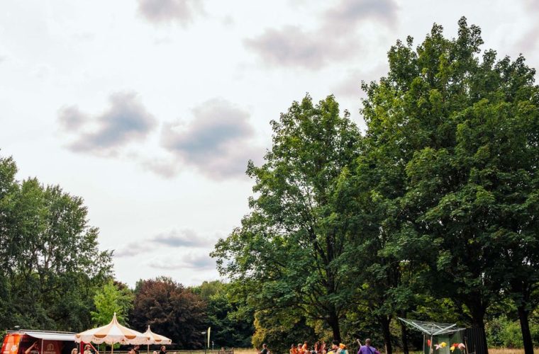 Kinderen spelen buiten onder de zomerzon tijdens een theatervoorstelling van de KinderKaravaan in een park in Apeldoorn